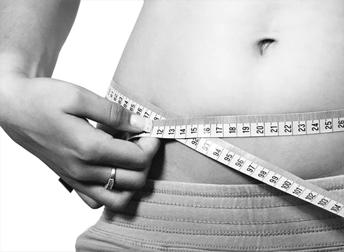 plus size woman measuring hips with a measuring tape